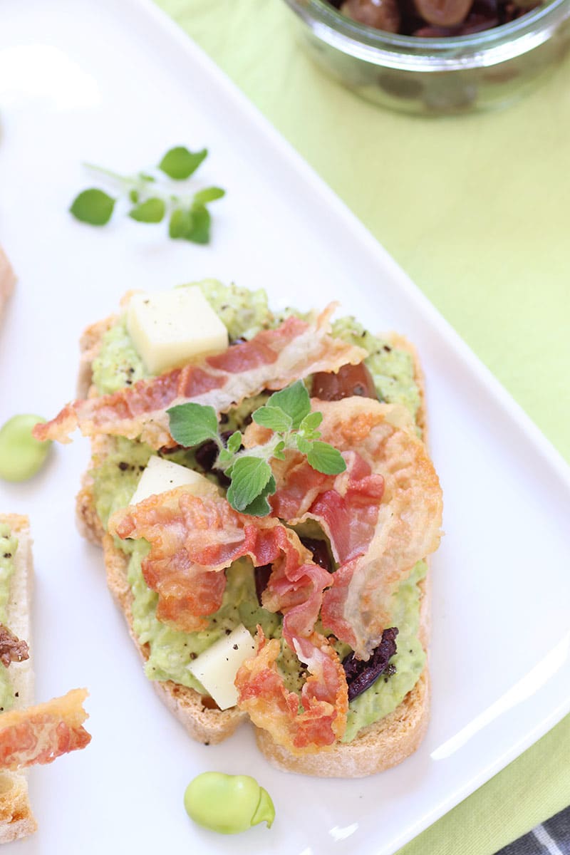 Crostini con crema di fave, olive e pancetta croccante